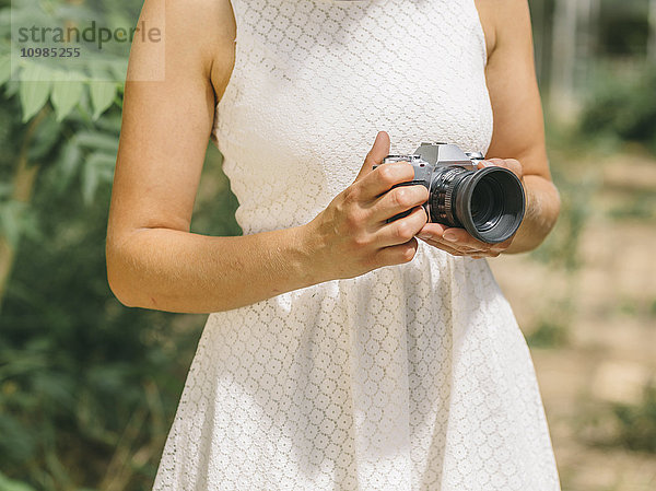 Junge Frau in weißem Kleid mit Kamera