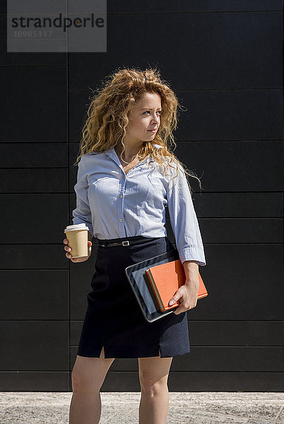 Geschäftsfrau mit Kaffee zum Mitnehmen  Buch und digitalem Tablett im Freien