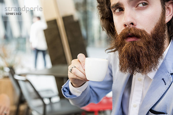 Stilvoller Geschäftsmann trinkt Espresso im Cafe