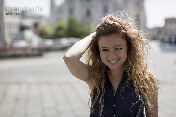 Italien  Mailand  Porträt der lächelnden jungen Frau mit der Hand im Haar