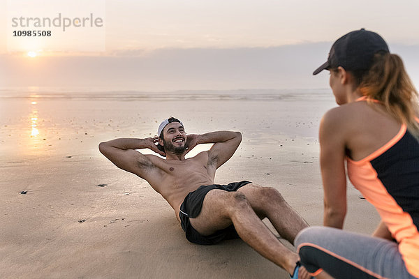 Sportlerpaar beim Training am Strand bei Sonnenuntergang