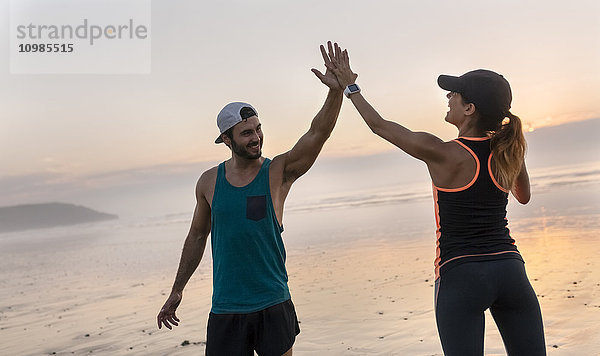 Athletenpaar bei Sonnenuntergang mit fünf Treffern am Strand