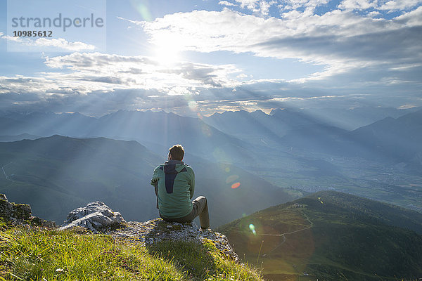 Österreich  Tirol  Wanderer auf Aussichtspunkt gegen die Sonne sitzend