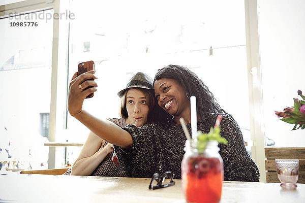 Zwei junge Frauen  die Selfie in einem Cafe nehmen.