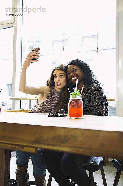 Zwei junge Frauen  die Selfie in einem Cafe nehmen.