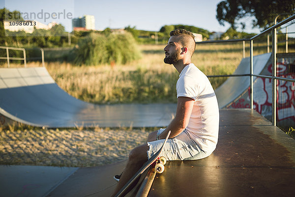 Nachdenklicher Skateboarder sitzt im Skatepark
