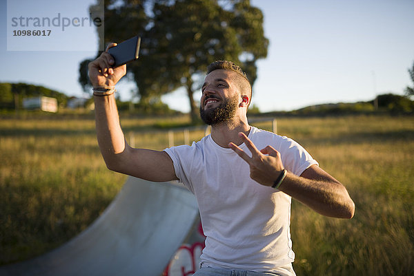 Mann nimmt Selfie und zeigt Siegeszeichen