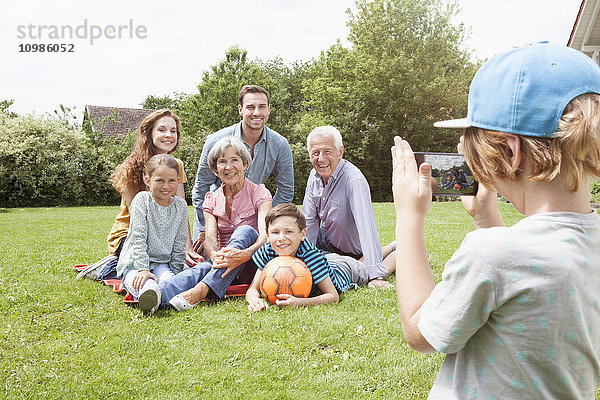 Junge fotografiert glückliche Großfamilie im Garten