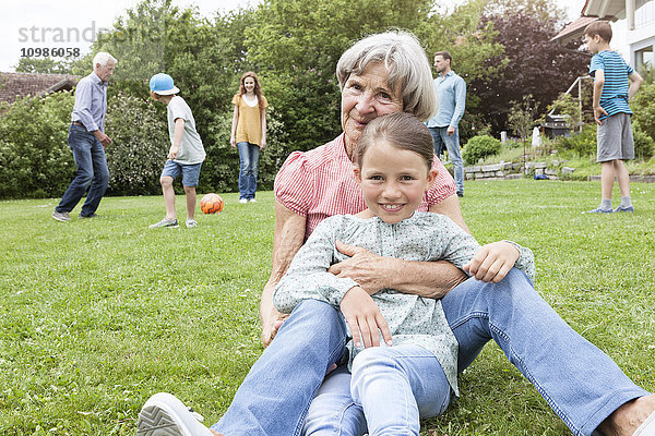 Porträt der glücklichen Großmutter mit Enkelin und Familie im Hintergrund