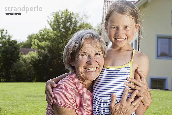 Porträt der glücklichen Großmutter und Enkelin im Garten