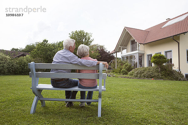 Seniorenpaar auf Bank im Garten sitzend