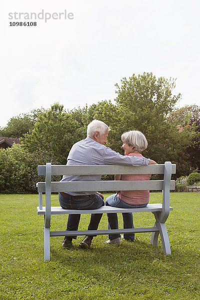 Glückliches Seniorenpaar sitzt auf der Bank im Garten