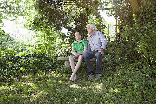 Großvater und Enkel sitzen zusammen im Freien.