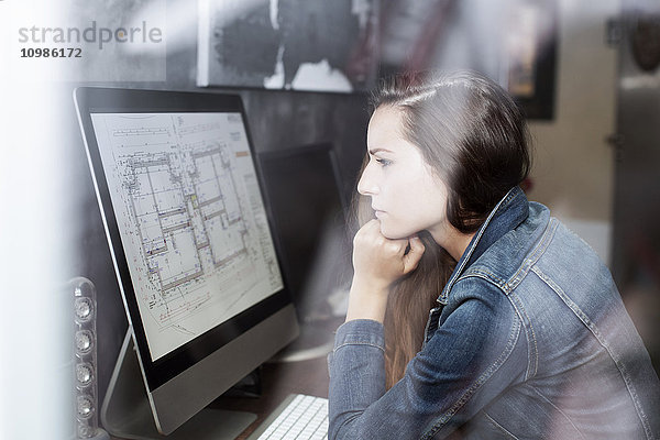 Junge Frau beim Betrachten des Bauplans auf dem Computerbildschirm
