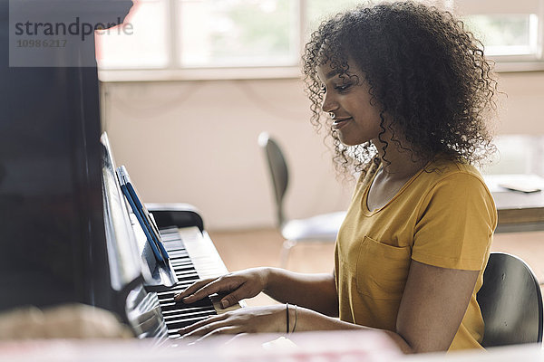 Junge Frau spielt Klavier  liest Noten vom digitalen Tablett