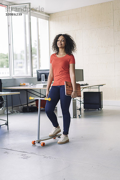 young woman carrying laptop  using kickboard in office