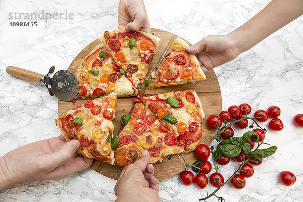 Vegetarische Pizza mit Mozzarella und Tomaten  Hände nehmen Pizza