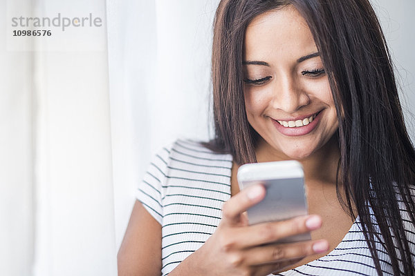 Porträt eines lächelnden Teenagermädchens beim Blick aufs Handy