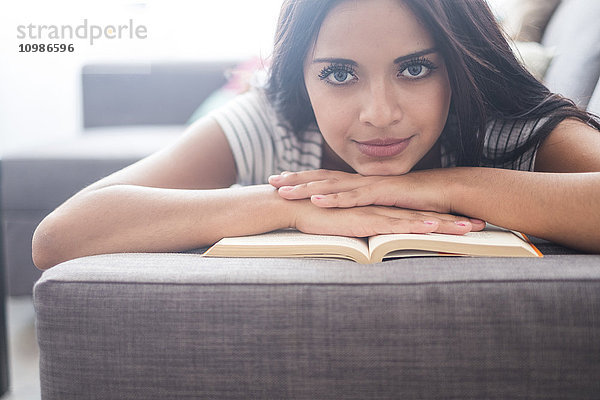 Porträt eines jungen Mädchens auf der Couch liegend mit einem Buch