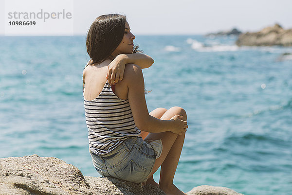 Frau mit Sommerkleidung und Blick aufs Meer am Strand von Blanes