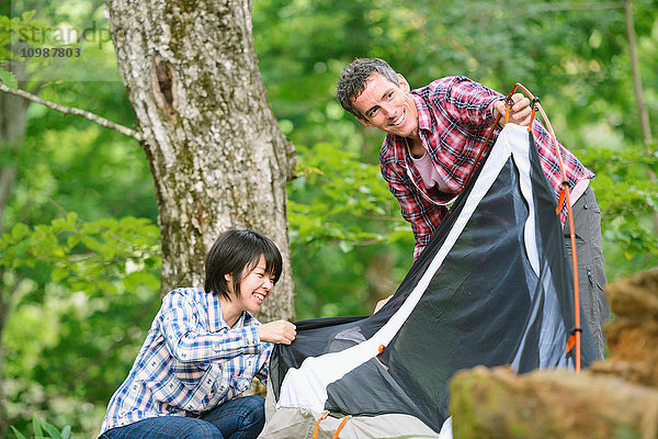 Freunde bauen ein Zelt auf einem Campingplatz auf