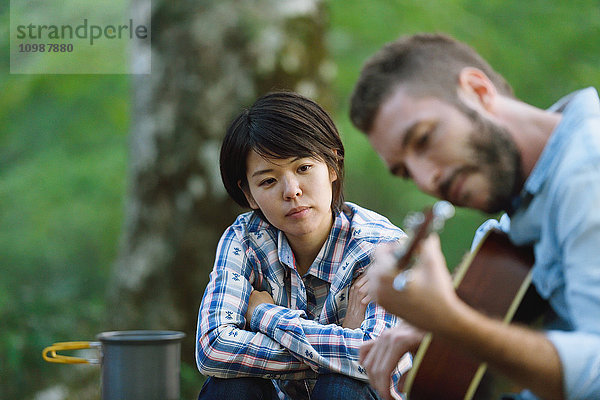 Freunde spielen Gitarre auf einem Campingplatz