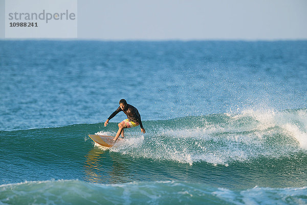 Japanischer Surfer reitet auf einer Welle