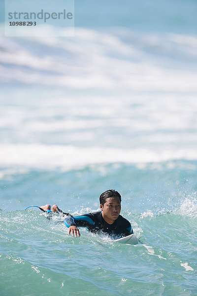 Japanischer Surfer beim Paddeln auf dem Meer