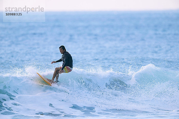 Japanischer Surfer reitet auf einer Welle
