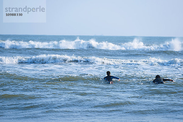 Japanische Surfer paddeln auf dem Meer