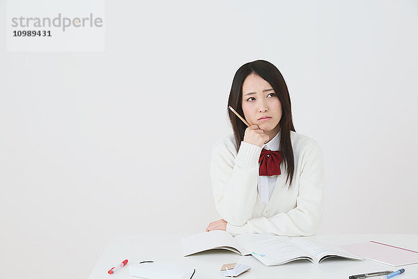 Japanischer Gymnasiast in Uniform vor weißem Hintergrund