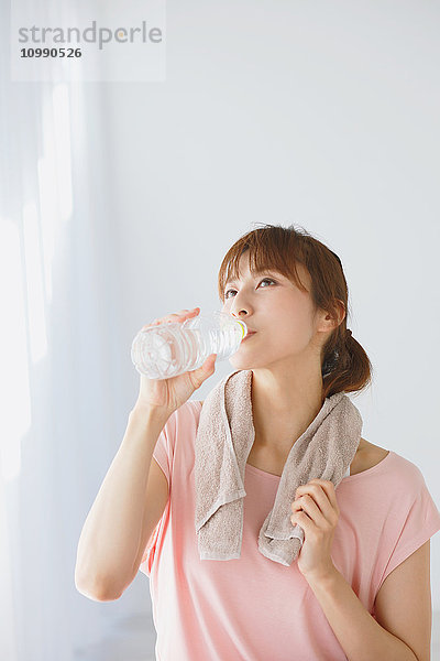 Junge Japanerin trinkt Wasser nach einer Yogapraxis