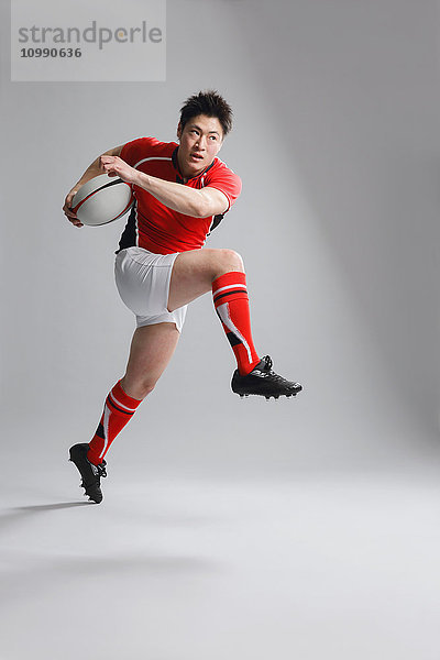 Porträt eines japanischen Rugbyspielers  der mit einem Ball läuft