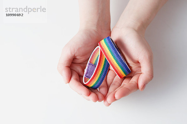 Hände halten Regenbogen-Armbänder