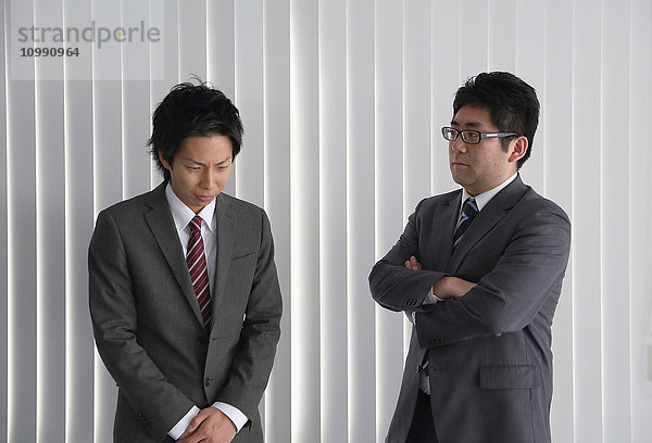 Junger japanischer Geschäftsmann wird von seinem Chef bewertet