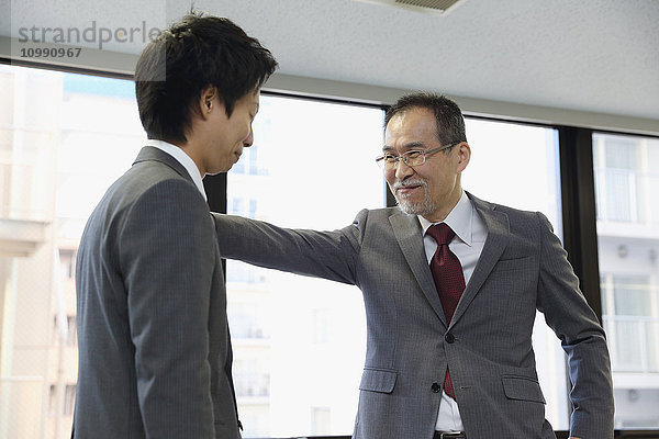 Junger japanischer Geschäftsmann wird von seinem Chef gelobt