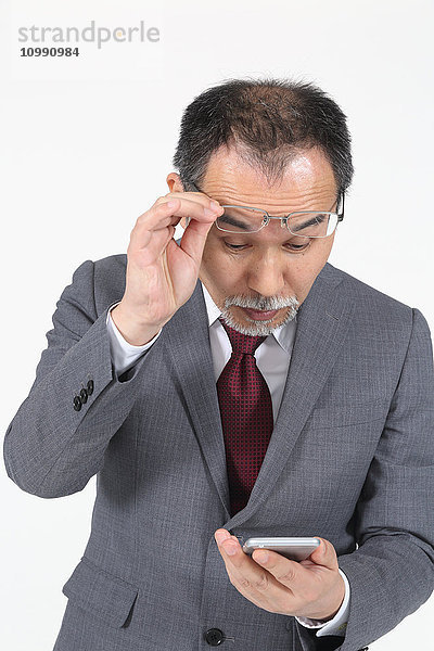 Japanischer Senior-Geschäftsmann hat Probleme mit seinem Smartphone