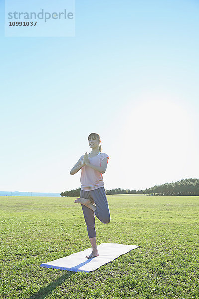 Junge Japanerin übt Yoga in einem Stadtpark