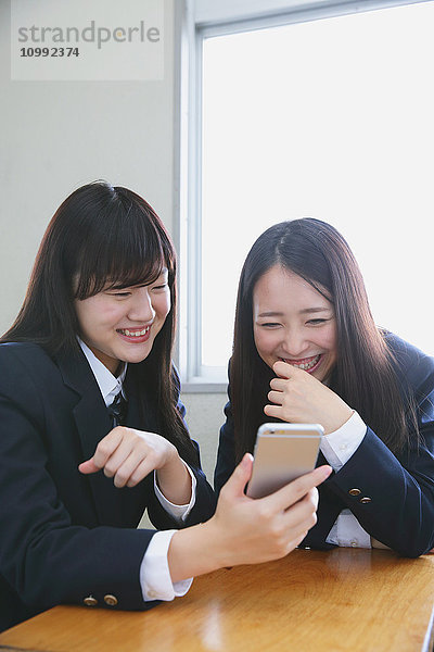 Japanische Gymnasiasten mit Smartphone im Klassenzimmer