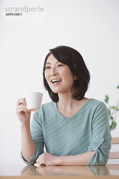 Ältere Japanerin beim Kaffee im Wohnzimmer