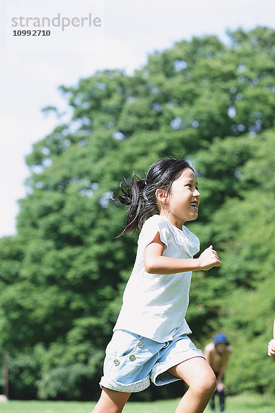 Japanisches Kind läuft in einem Stadtpark