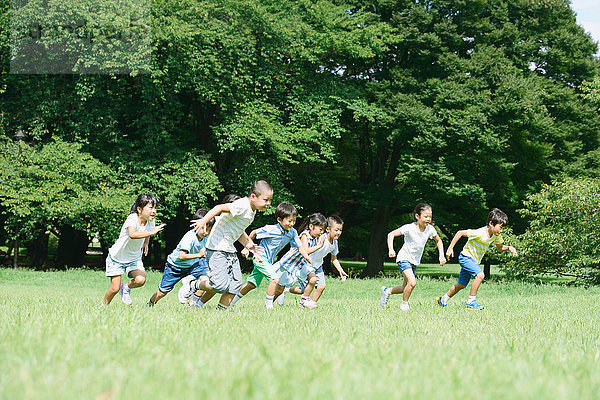 Japanische Kinder laufen in einem Stadtpark
