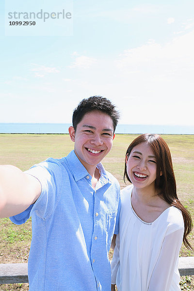 Junges japanisches Paar macht Selfie am Meer