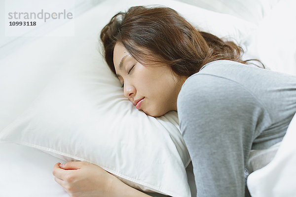 Junge attraktive japanische Frau schläft im Bett