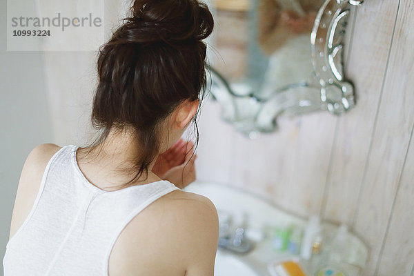 Junge attraktive japanische Frau wäscht ihr Gesicht im Badezimmer