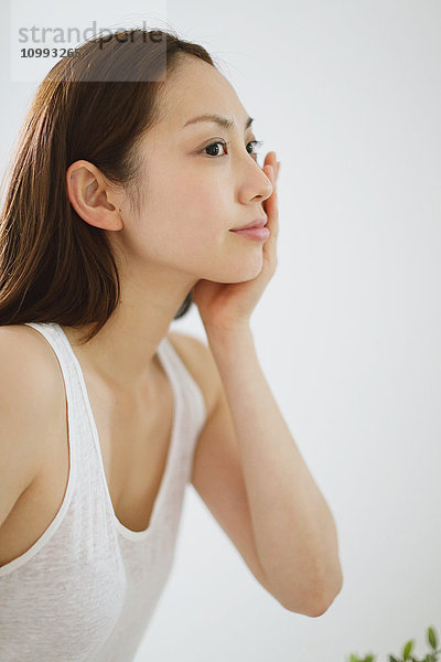 Junge attraktive Japanerin bei der Hautpflege im Badezimmer