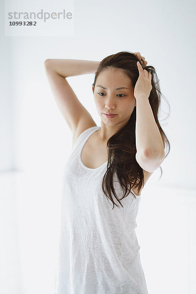 Junge attraktive japanische Frau  die sich im Badezimmer die Haare macht