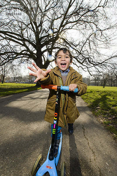 Kind spielt mit Kickboard in einem Park