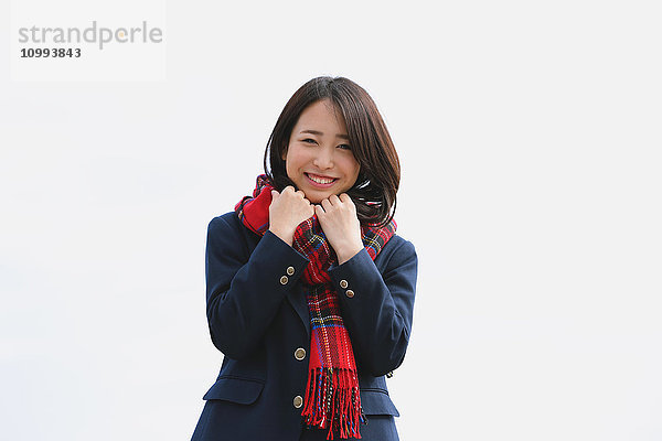 Japanische Oberschülerin mit Schal vor blauem Himmel