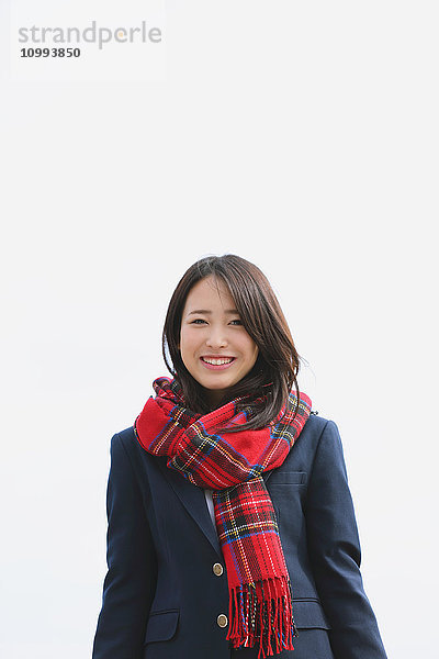 Japanische Oberschülerin mit Schal vor blauem Himmel